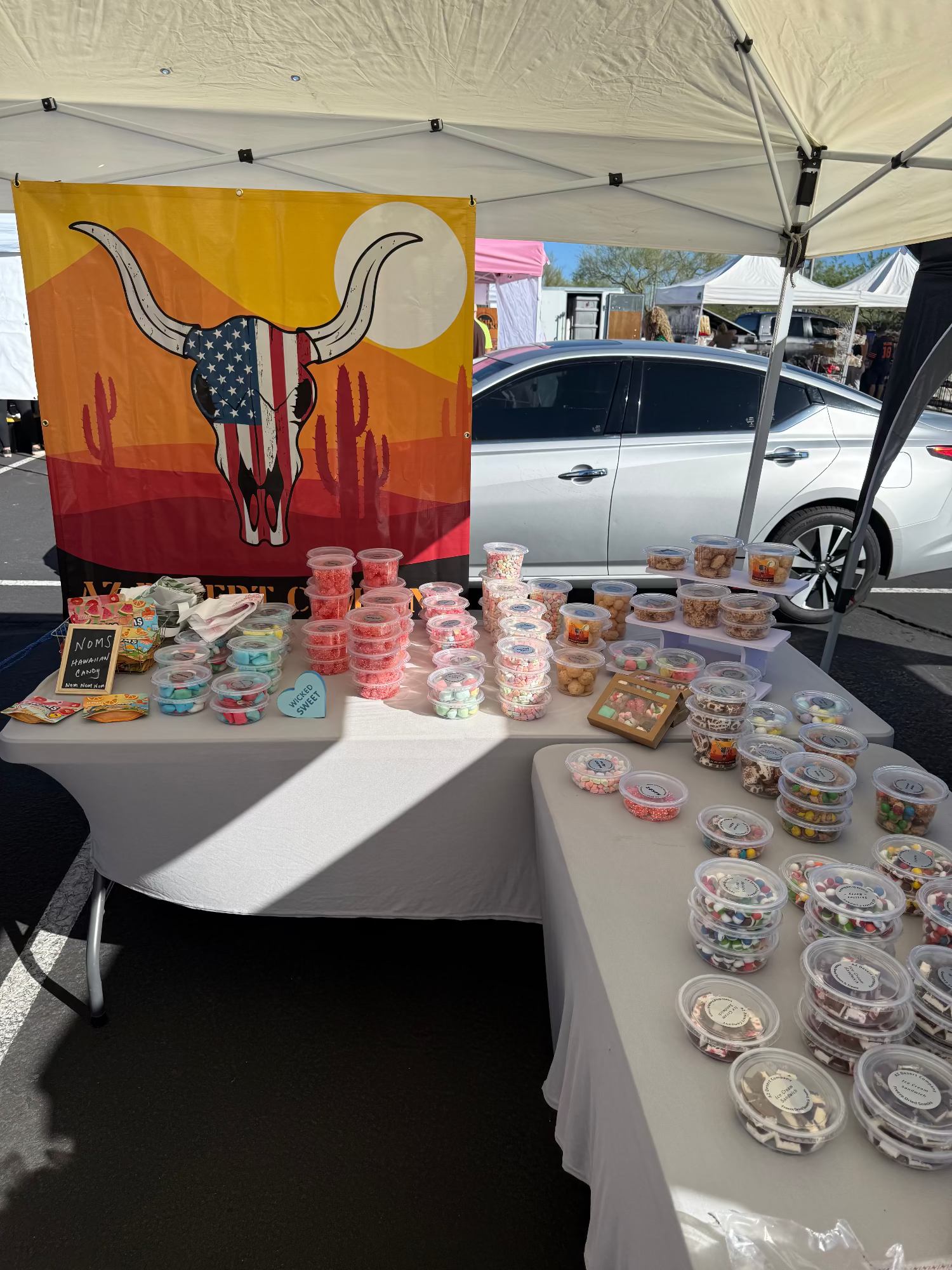 Table with containers of freeze dried candy under a tent with a bull skull design