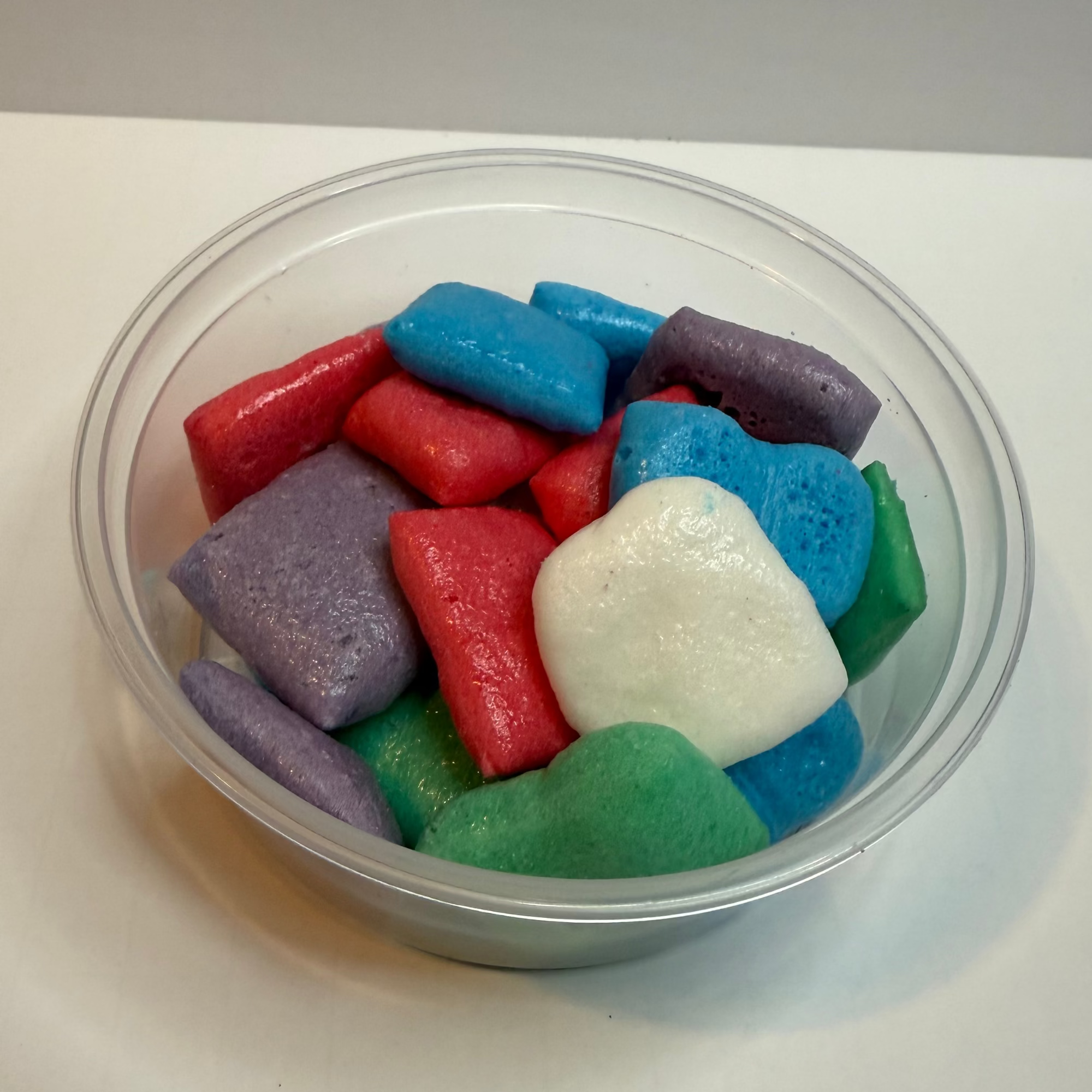 Clear plastic container with freeze dried airheadz on a white surface