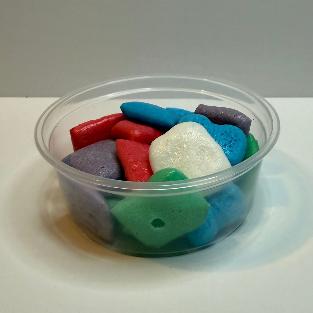 Clear plastic container with freeze dried airheadz on a white surface.