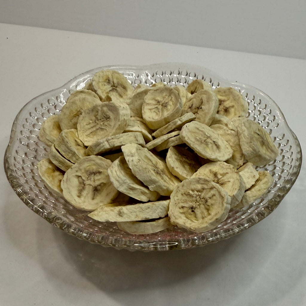 Freeze dried banana slices in a decorative glass bowl on a white surface