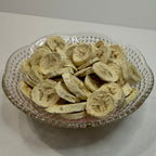 Freeze dried banana slices in a decorative glass bowl on a white surface