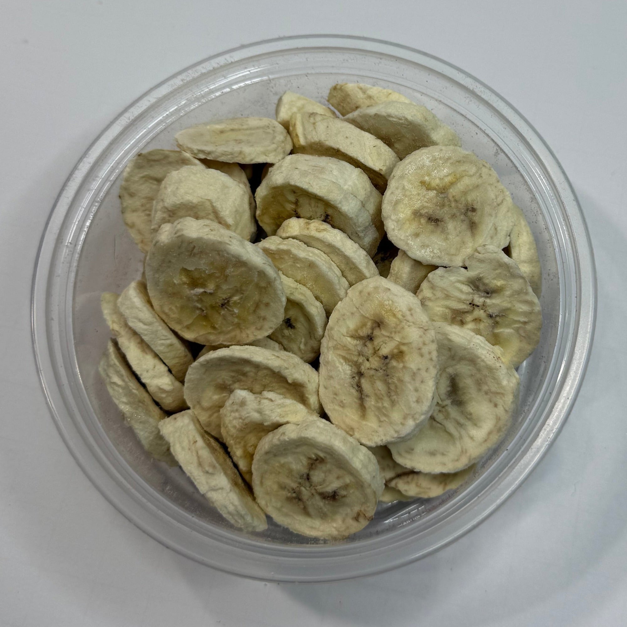 Clear container with freeze dried banana slices on a white background
