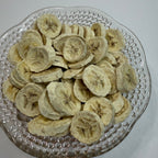 Freeze dried banana slices on a decorative glass plate with a plain background