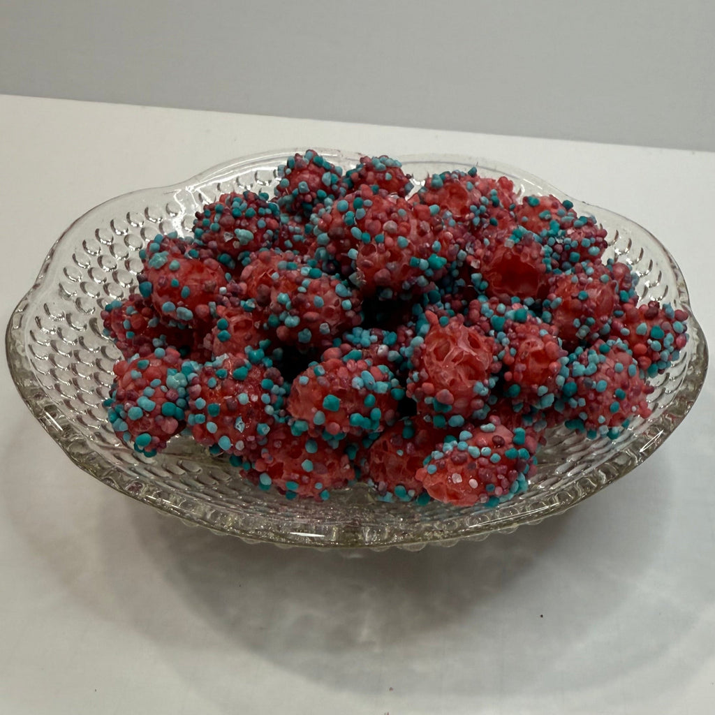 Decorative glass bowl with freeze dried berry blue nerds gummy clusters on a white surface