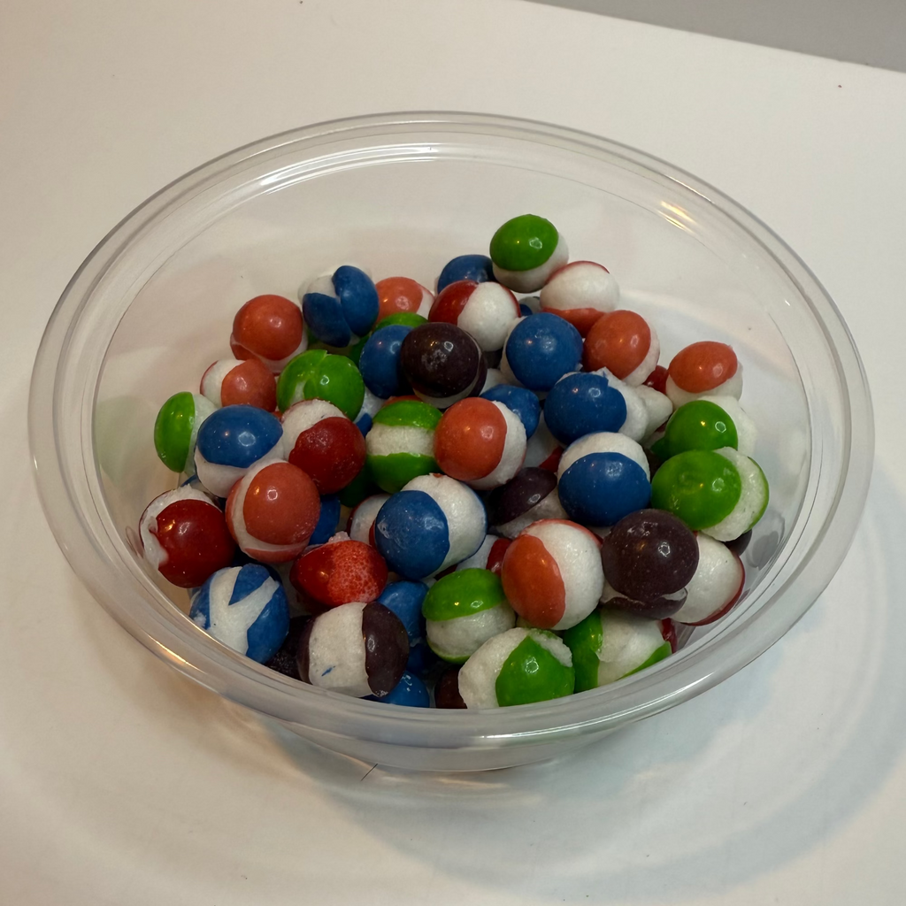 Clear bowl filled with freeze dried berry skittles on a white surface