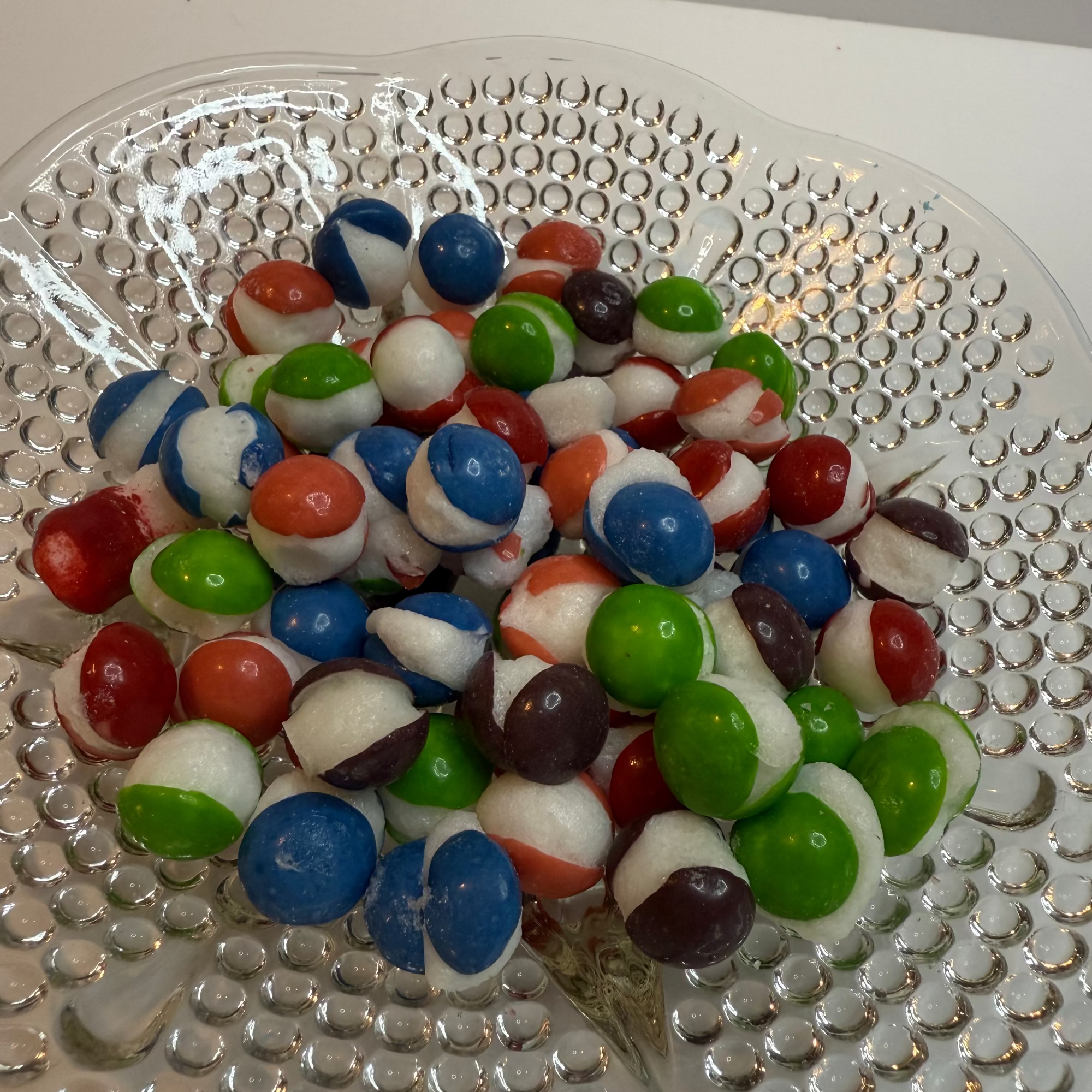 Freeze dried berry skittles on a textured glass plate