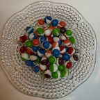 Freeze dried berry skittles on a decorative glass plate with a white background