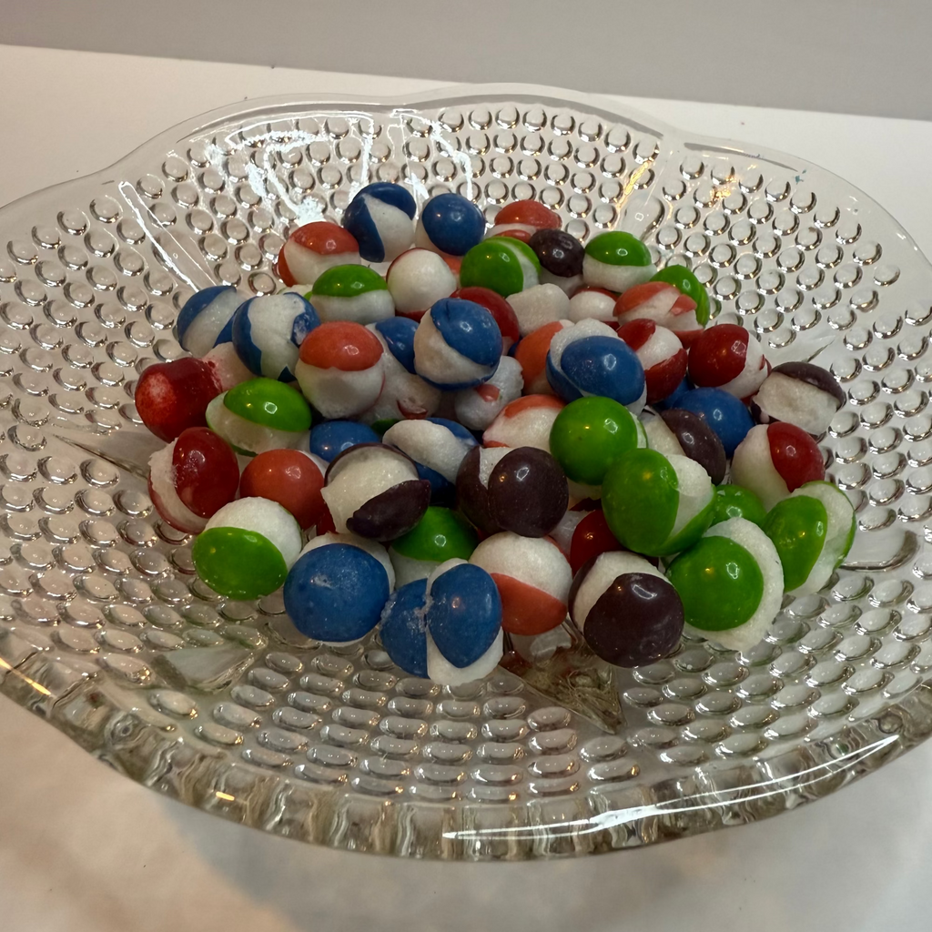 Freeze dried berry skittles on a clear glass plate with a white background