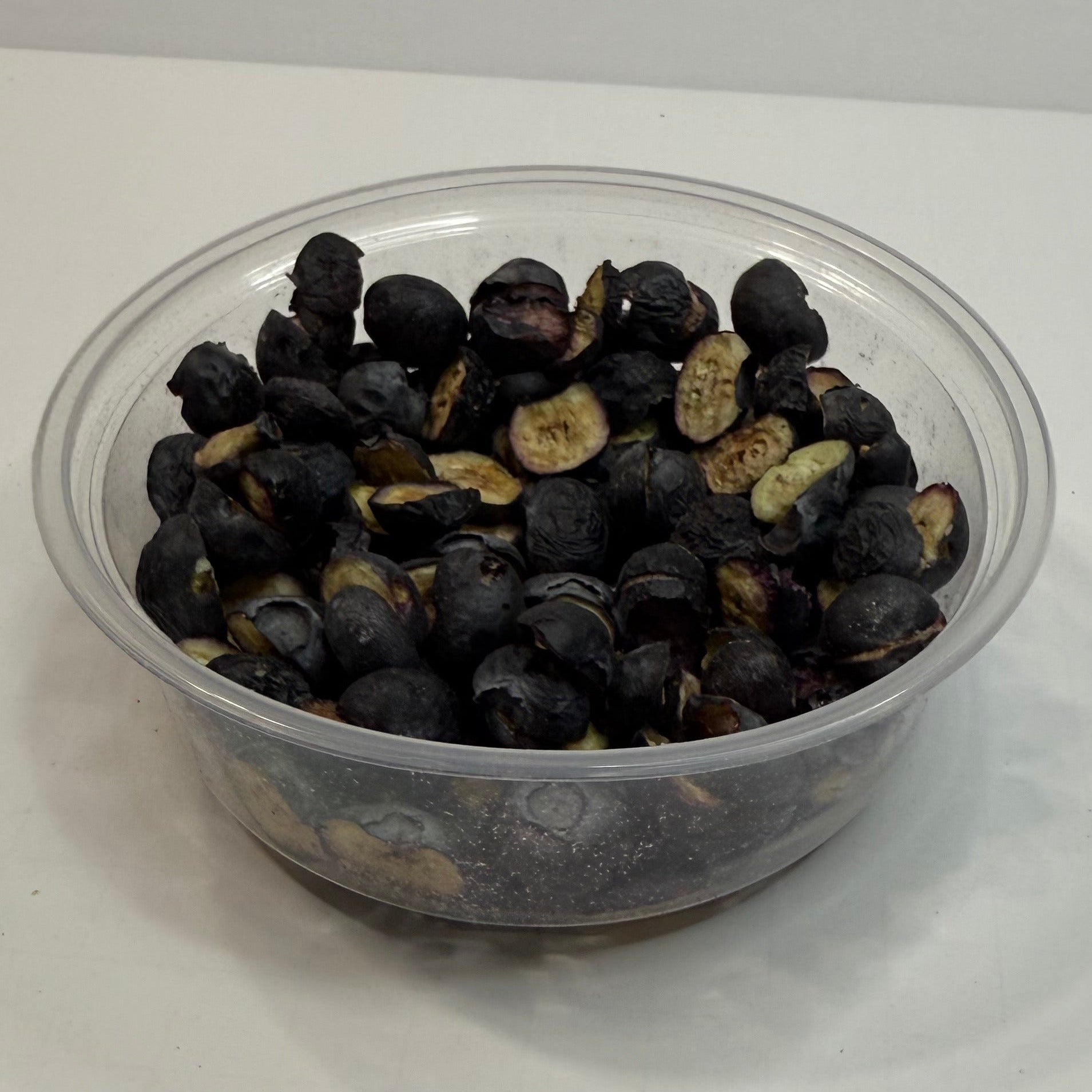 Clear plastic container filled with freeze dried blueberries on a white surface