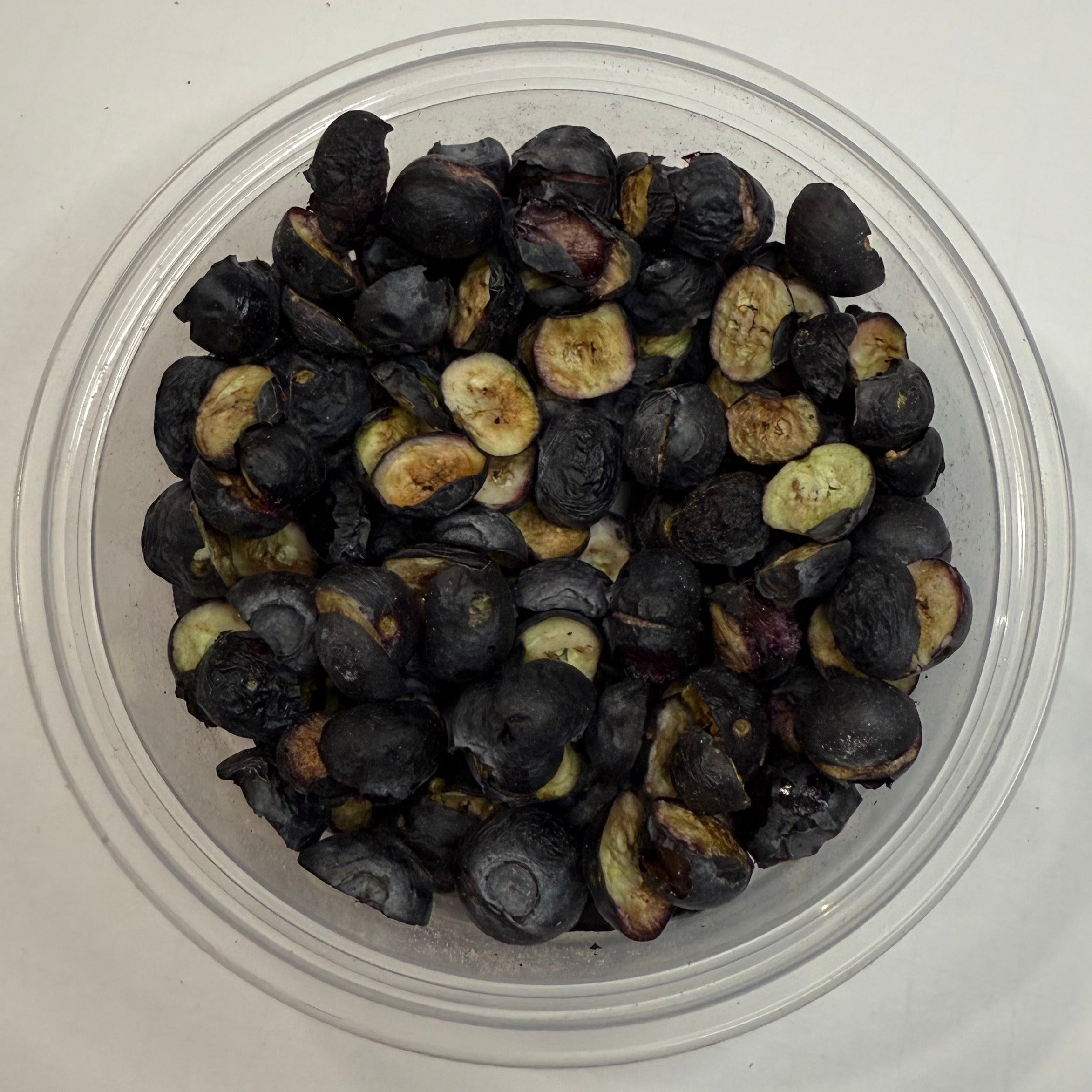 Small container with freeze dried blueberries on a white background