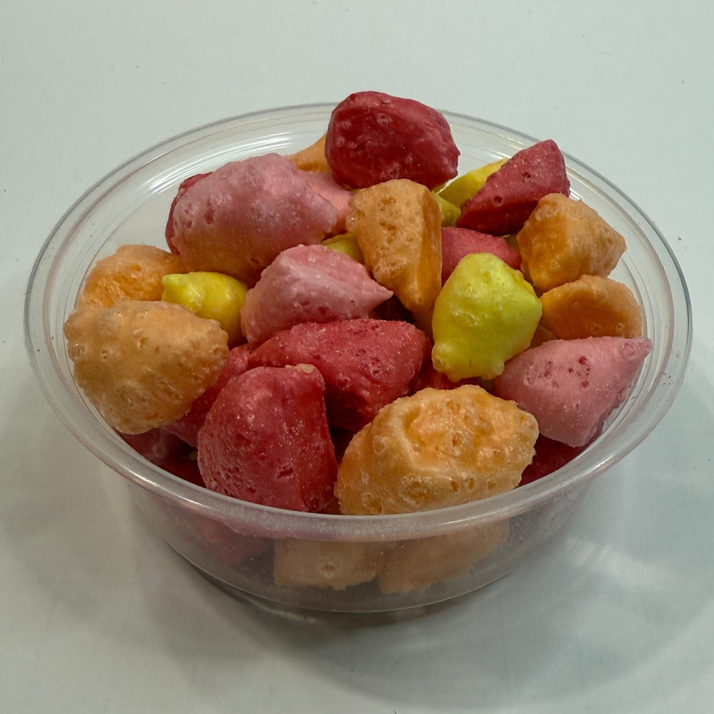 Clear plastic cup filled with freeze dried starburst bites on a white background