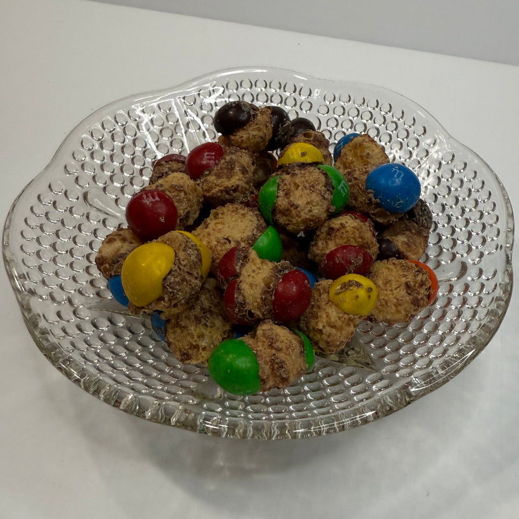 Decorative glass plate with freeze dried caramel M&Ms on a white surface
