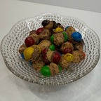 Decorative glass plate with freeze dried caramel M&Ms on a white surface