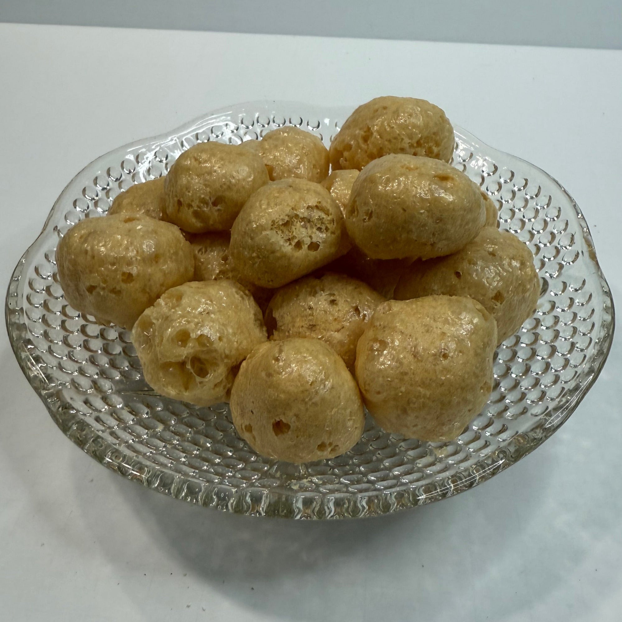 Glass dish with freeze dried caramels on a white background