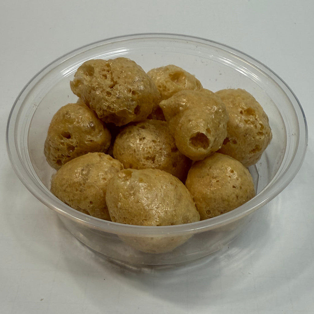 Clear plastic cup filled with freeze dried caramels on a white background