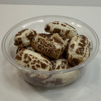 Glass container with freeze dried chocolate chews on a white surface
