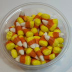 Clear plastic container filled with freeze dried candy corn on a white background