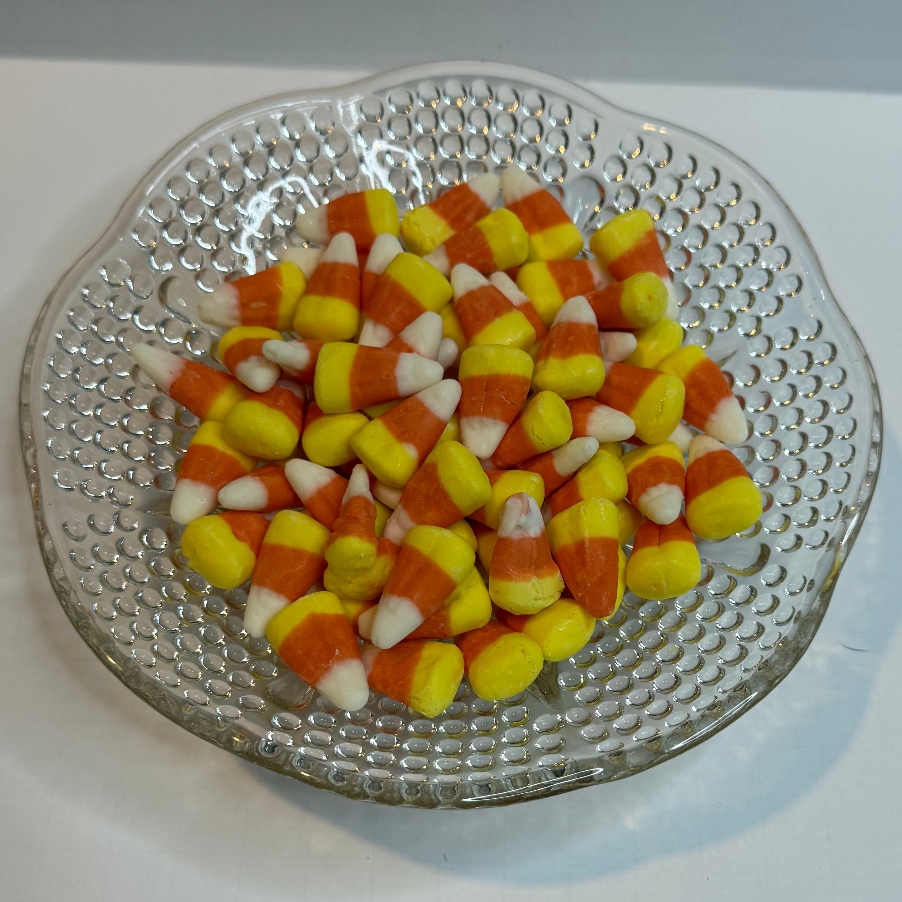 Clear glass plate with freeze dried candy corn on a white background
