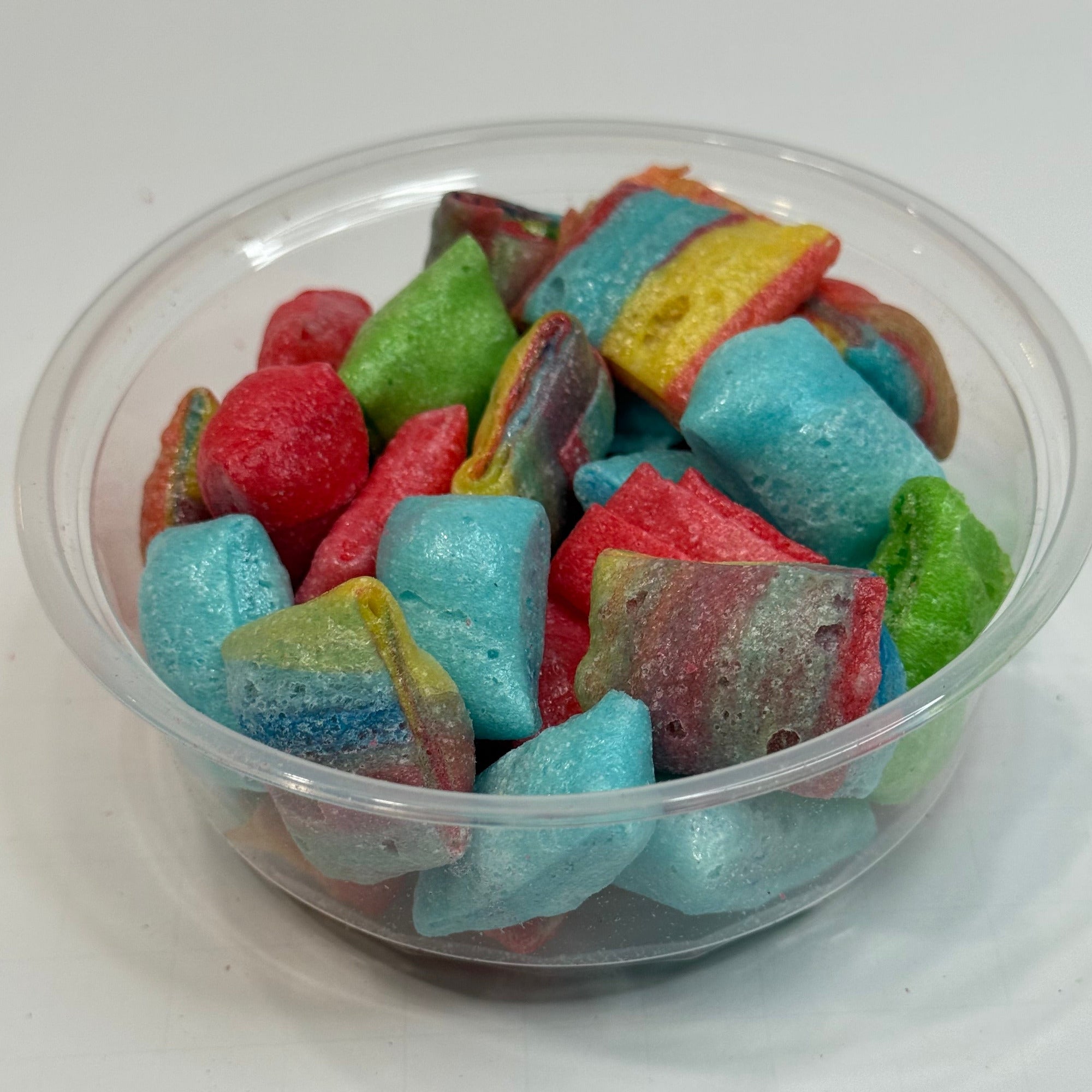 Clear container filled with freeze dried fruit roll up bites on a white background