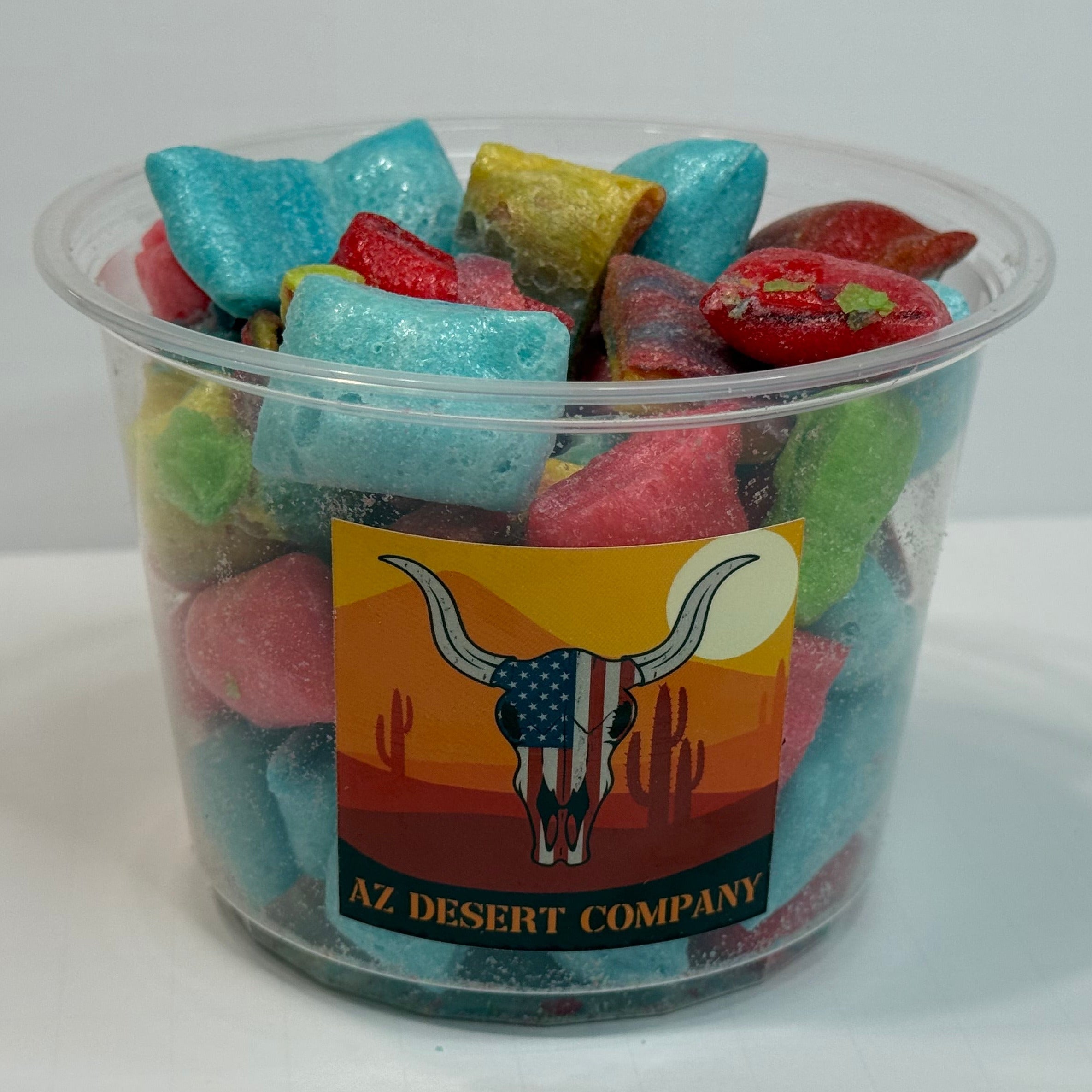 Clear plastic cup filled with freeze dried fruit rollup pieces on a white background, featuring an 'AZ Desert Company' label.