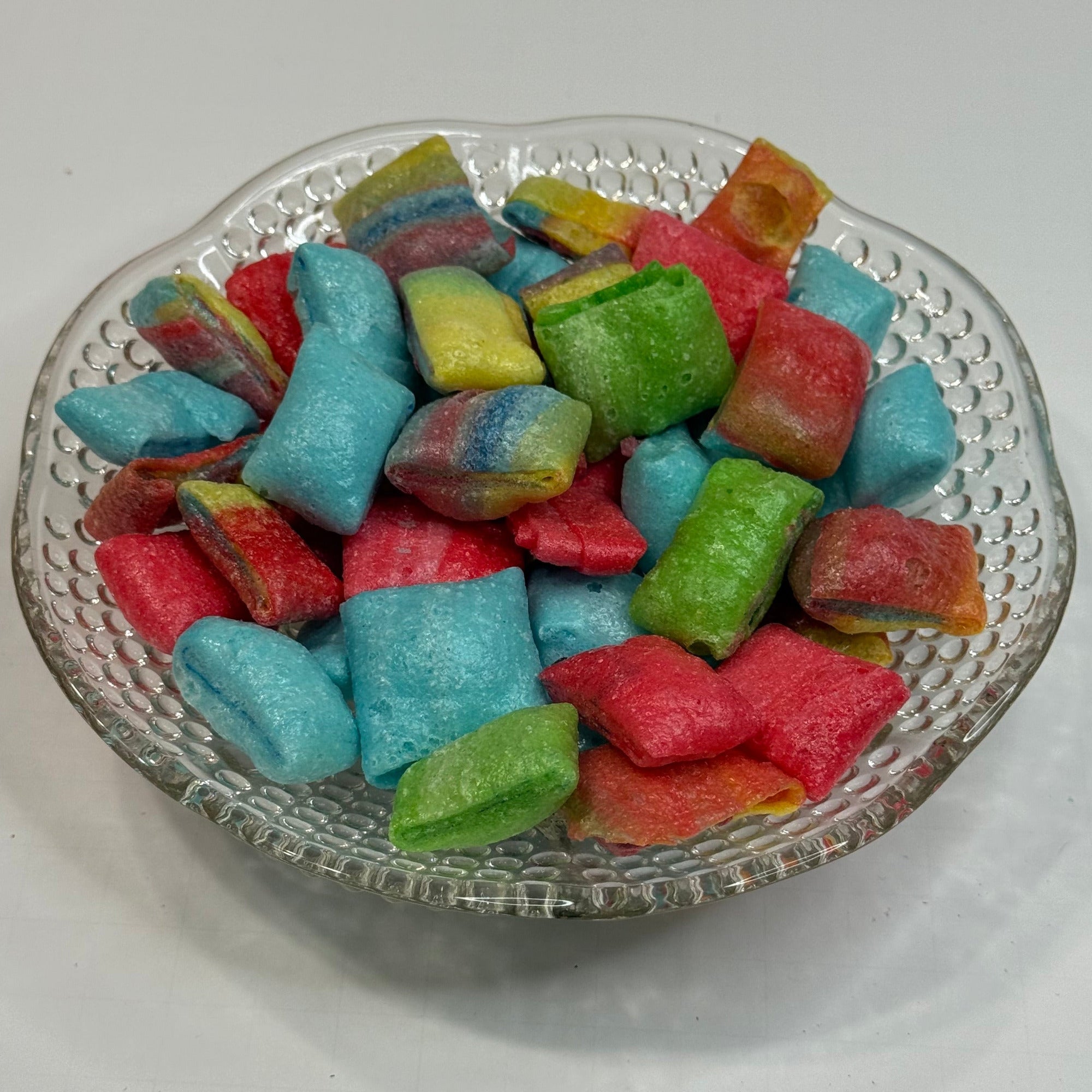 Freeze dried fruit rollup bites on a glass dish with a white background