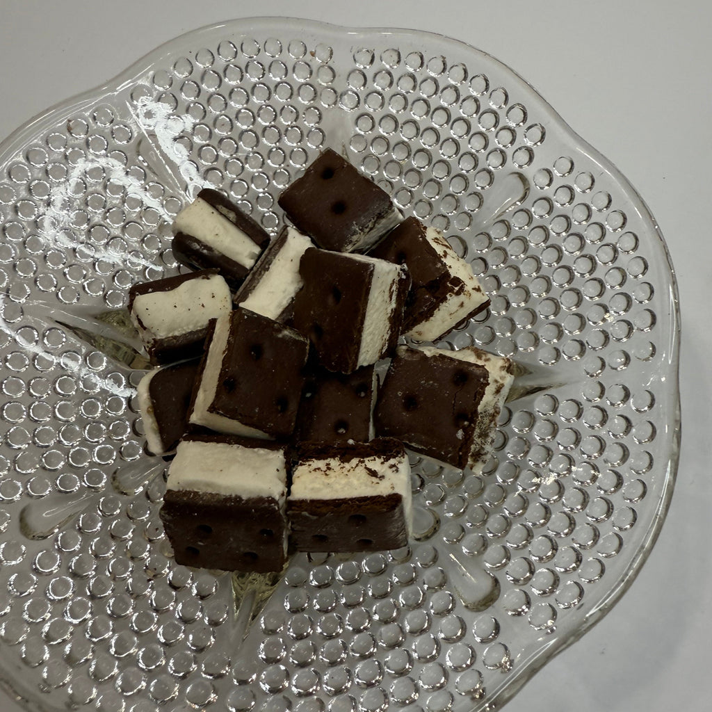 Freeze dried chocolate and vanilla ice cream sandwich bites on a decorative glass plate.