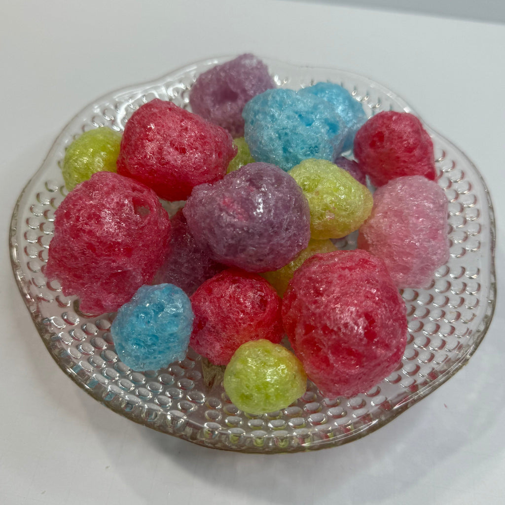 Colorful freeze dried jolly ranchers on a textured glass plate with a white background