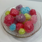 Colorful freeze dried jolly ranchers on a textured glass plate with a white background