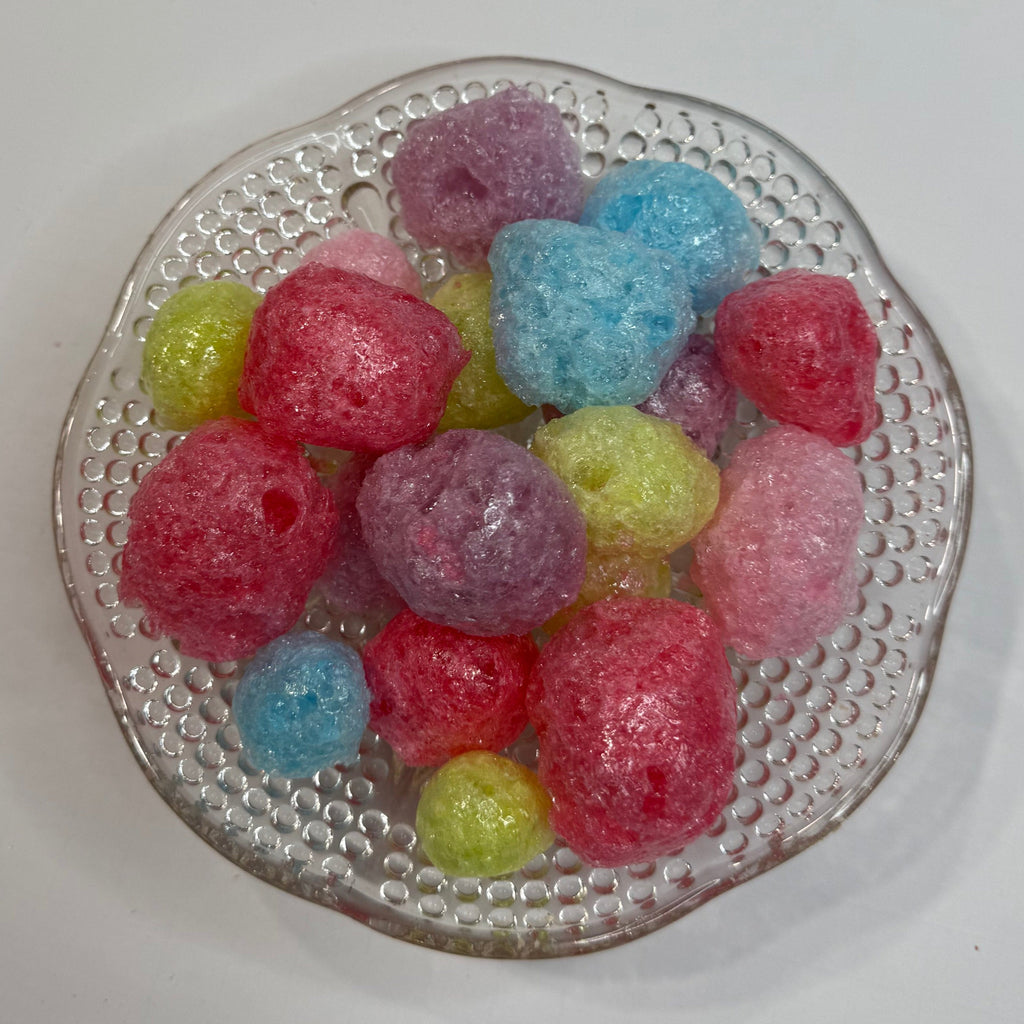 Colorful freeze dried jolly ranchers on a textured glass plate with a white background