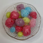 Colorful freeze dried jolly ranchers on a textured glass plate with a white background