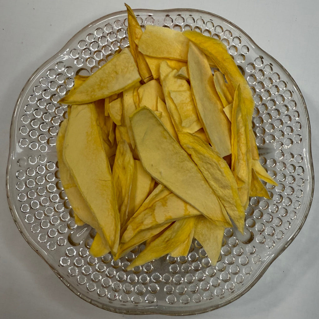 Clear glass plate with sliced freeze dried mango on a white background