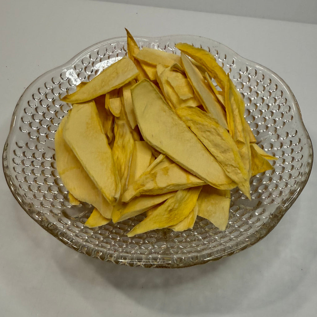 Clear glass plate with freeze dried mango slices on a white surface