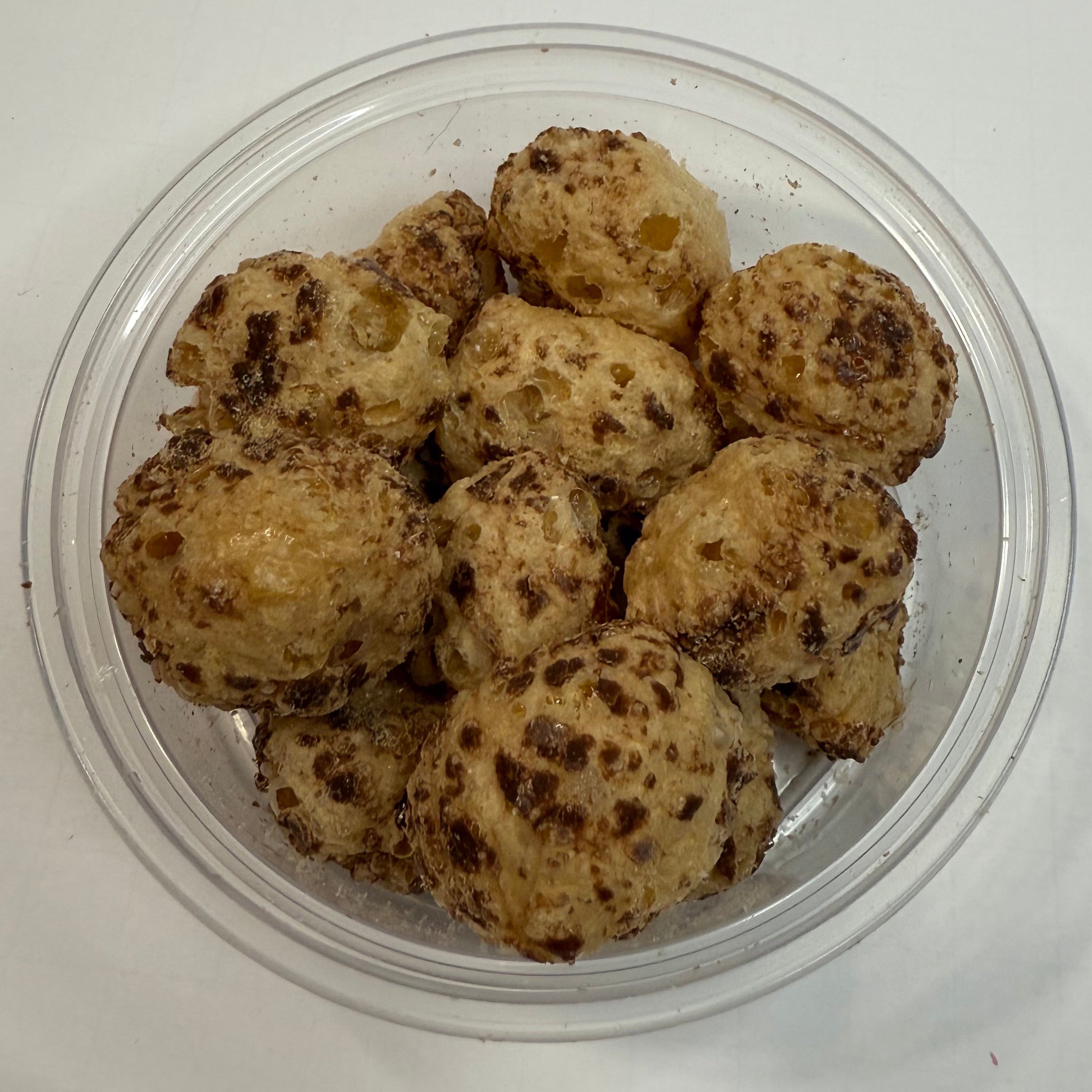 Clear plastic container with freeze dried milk dudz on a white surface