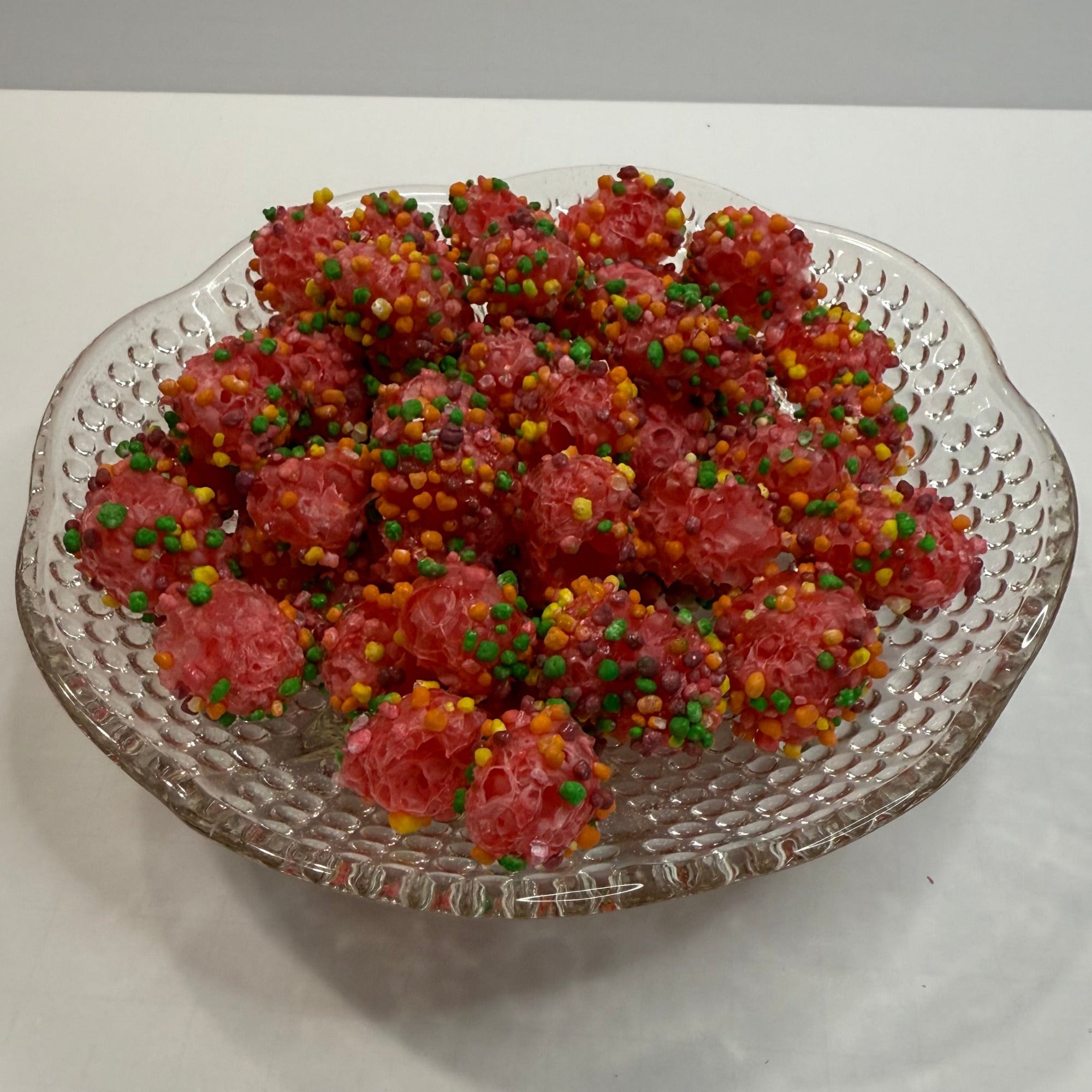 Decorative glass plate with freeze dried nerds gummy clusters on a white background