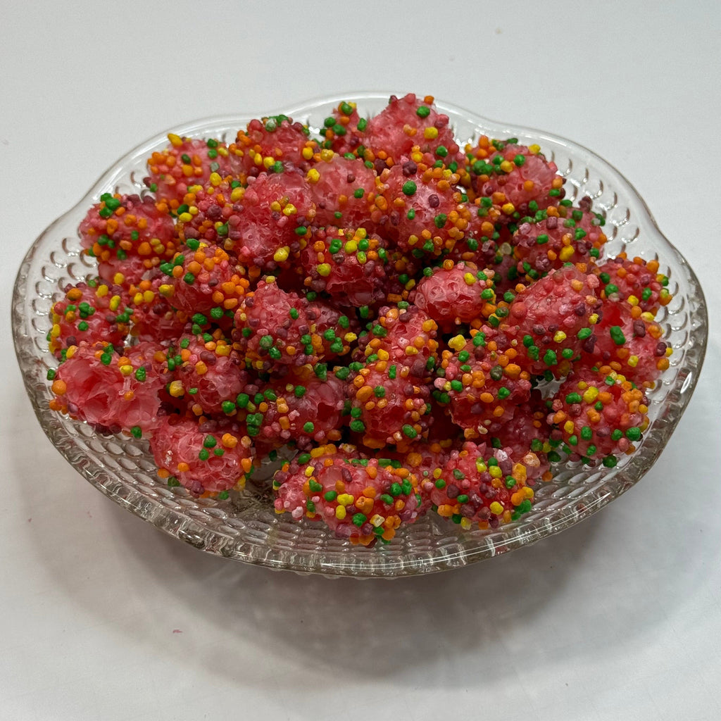 Clear glass dish filled with freeze dried nerds gummy clusters on a white surface.
