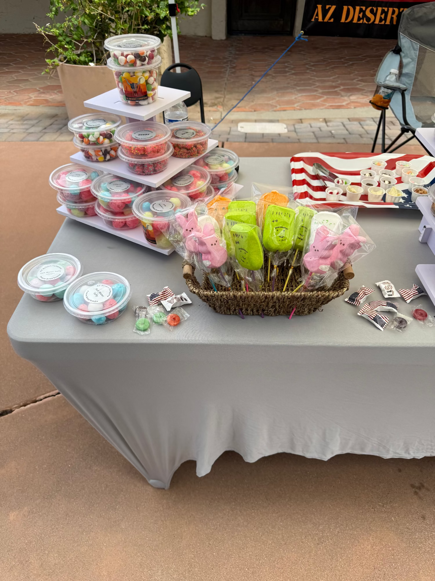 Table with various freeze dried food items including containers of snacks and a basket of freeze dried peeps outdoors.