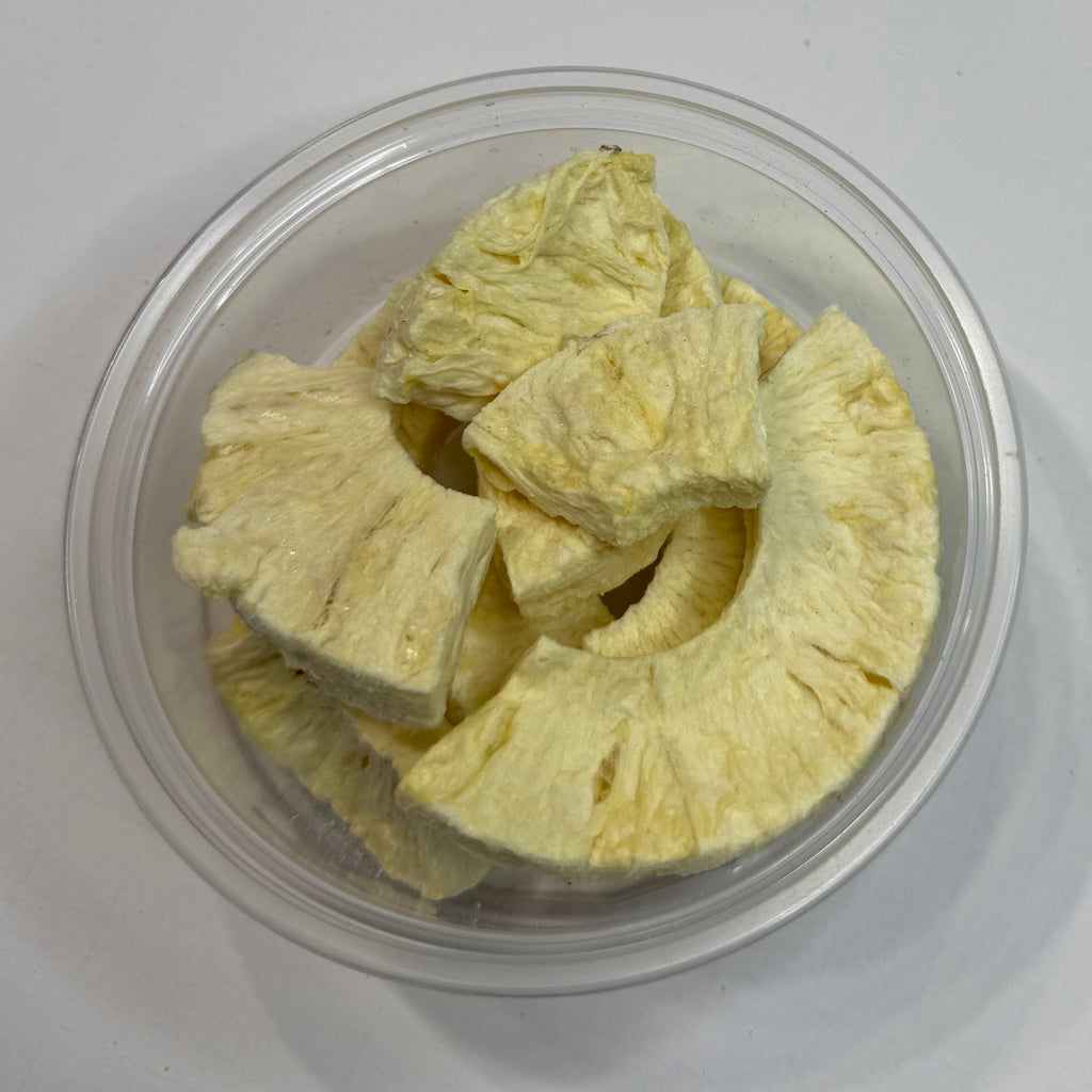 Clear container with freeze dried pineapple on a white background
