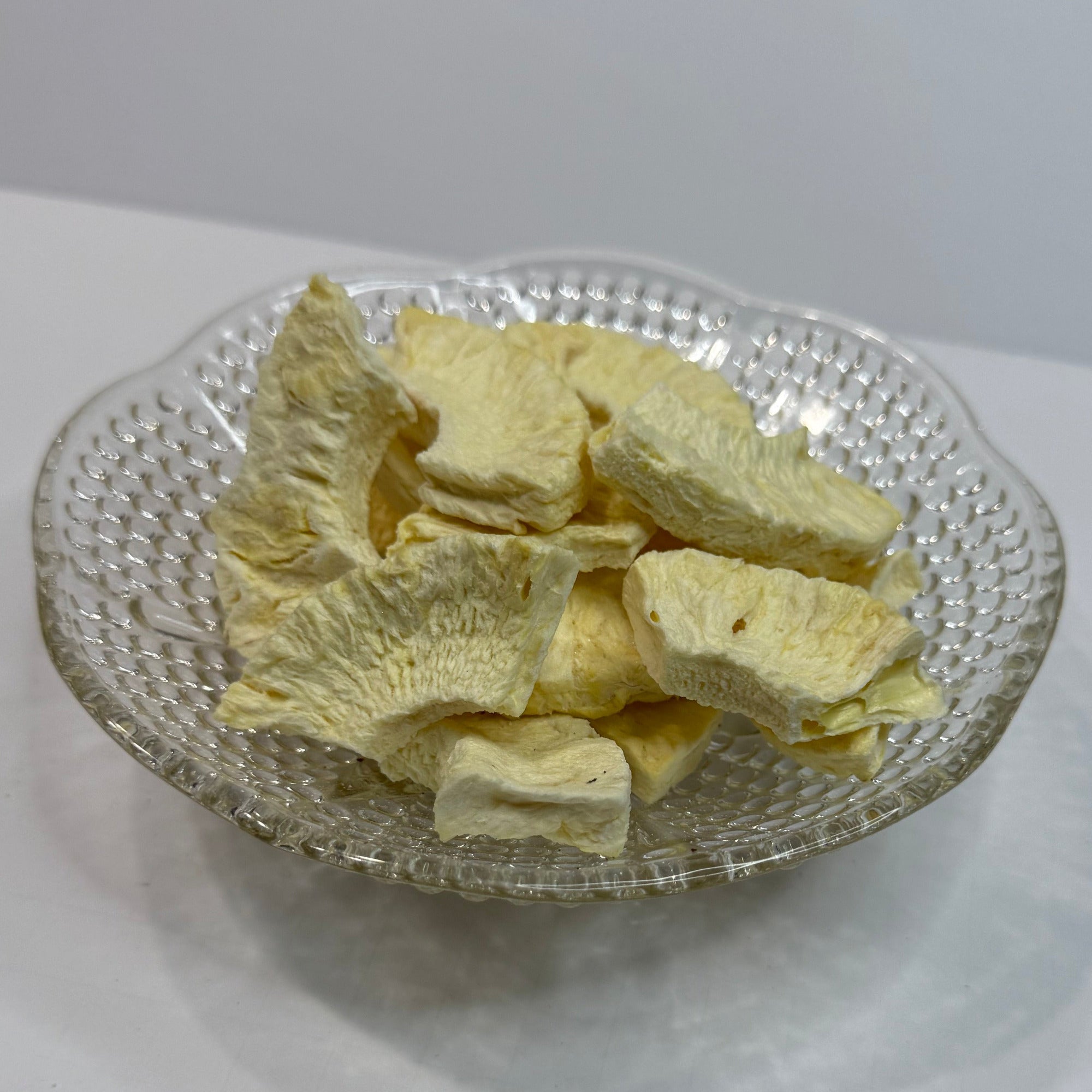 Decorative glass bowl with freeze dried pineapple on a white background