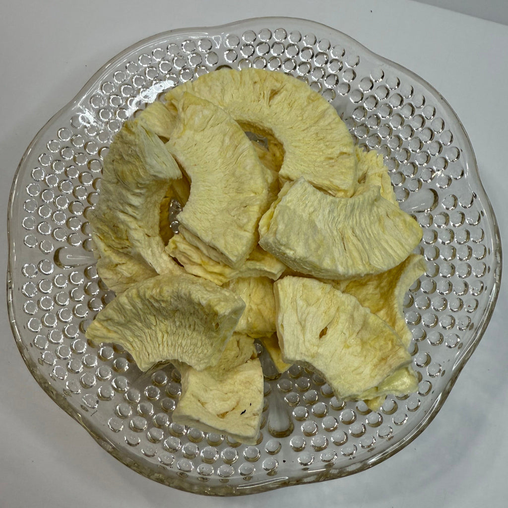Freeze dried pineapple slices on a textured glass plate with a white background