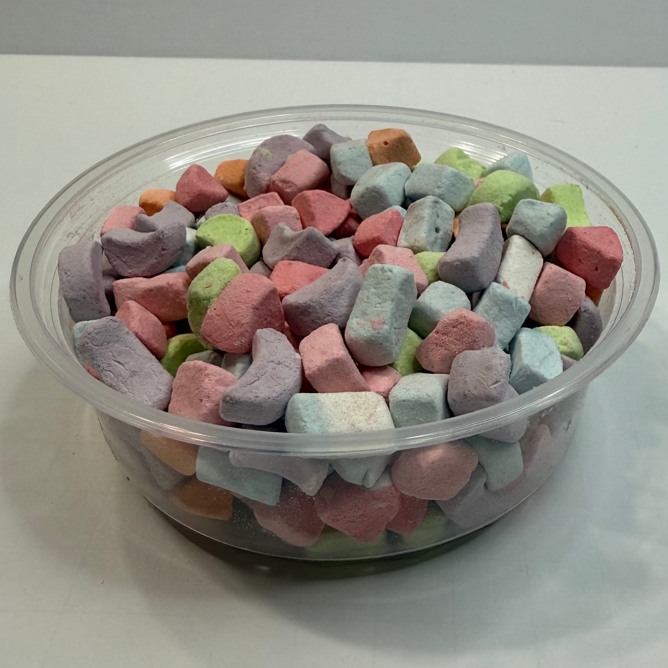 Clear container filled with colorful freeze dried marshmallows on a white background