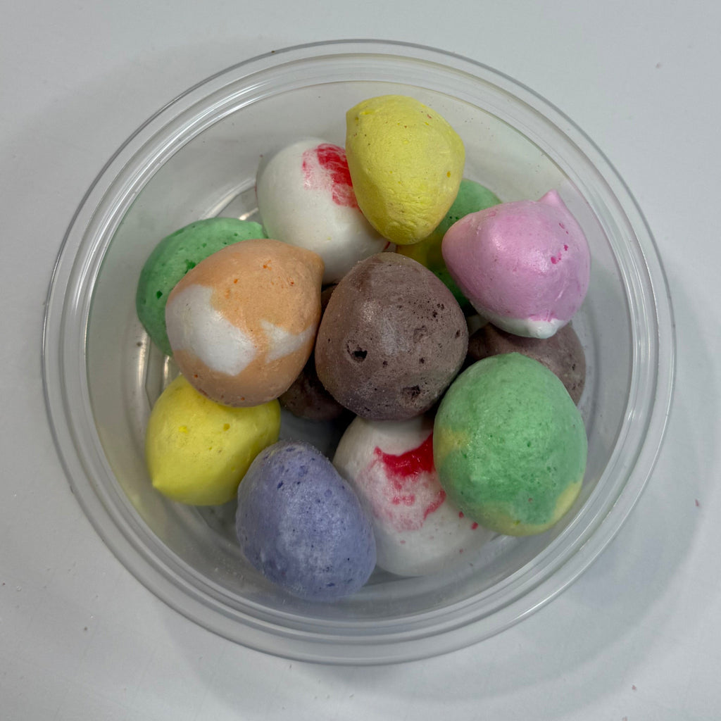 Clear plastic container with colorful freeze dried salt water taffy on a white surface