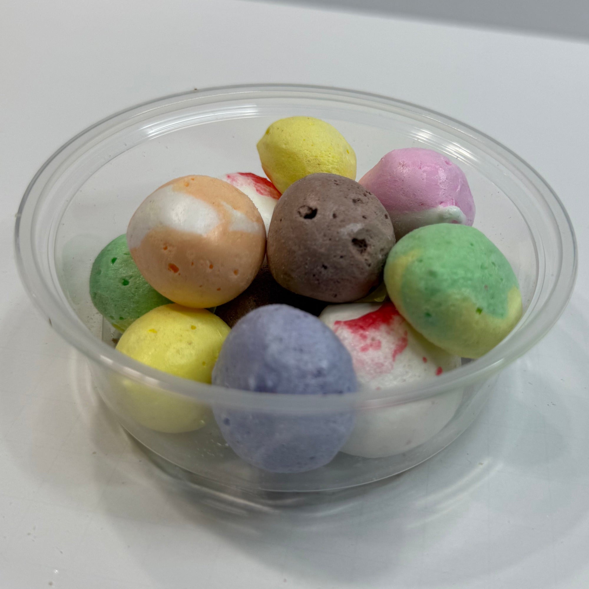 Clear plastic cup filled with freeze dried salt water taffy on a white surface