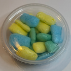 Clear plastic container with freeze dried sour air headz on a white background