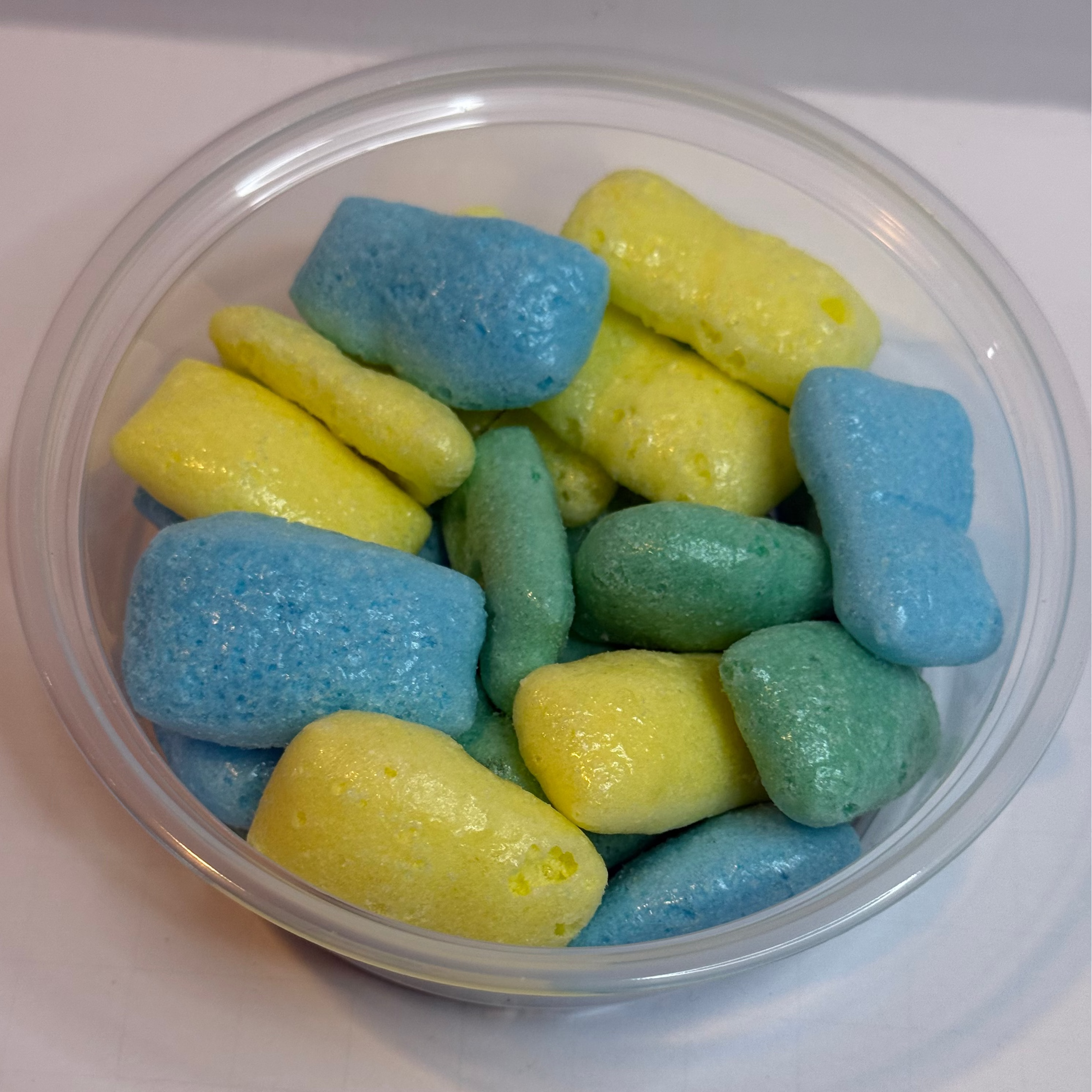 Clear container with freeze dried sour air headz on a white background