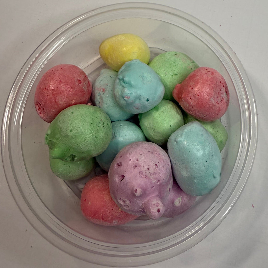 Clear plastic container with freeze dried sour salt water taffy on a white surface