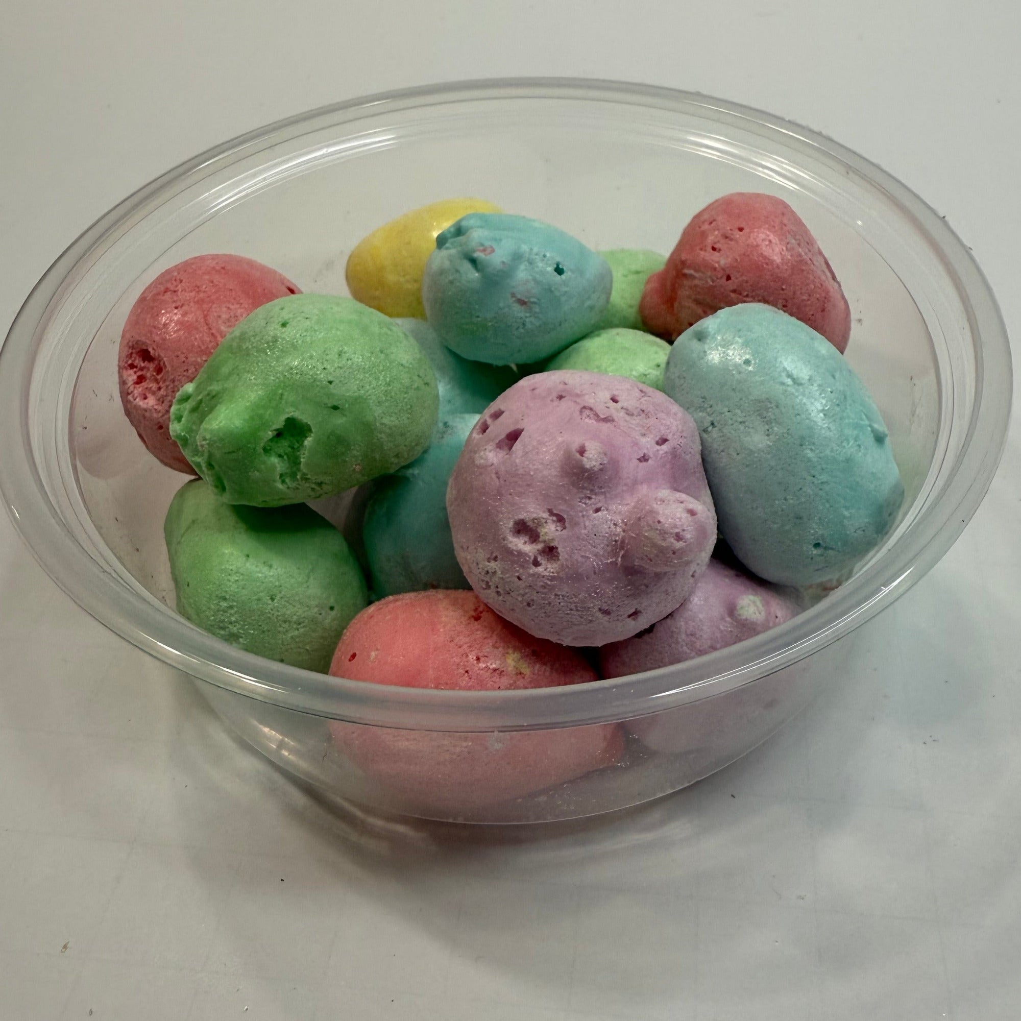 Clear plastic container filled with freeze dried salt water taffy on a white surface.