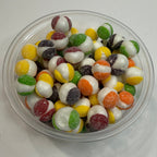 Clear container filled with freeze dried sour skittles on a white surface
