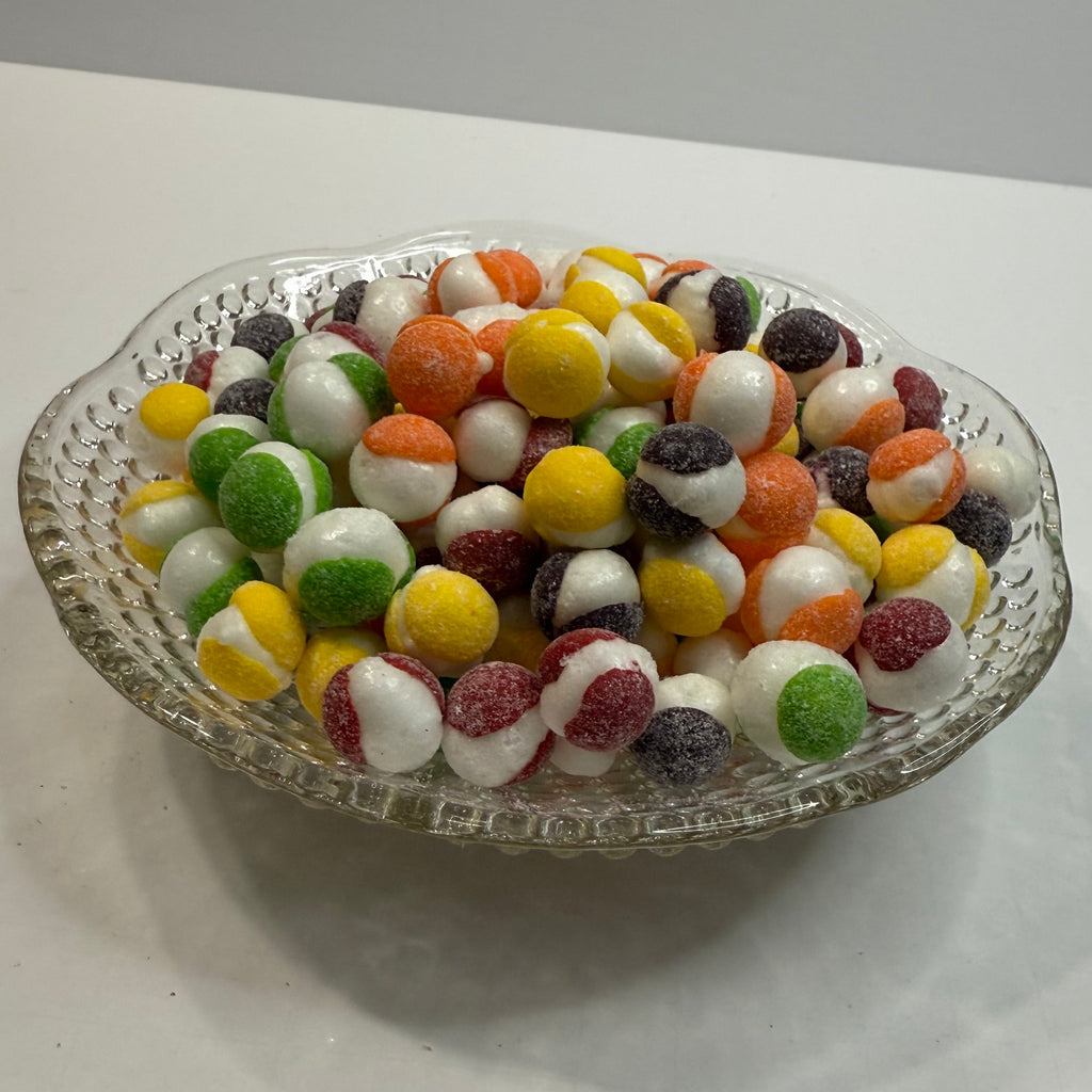 Glass dish filled with freeze dried sour skittles on a white surface