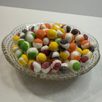 Glass dish filled with freeze dried sour skittles on a white surface