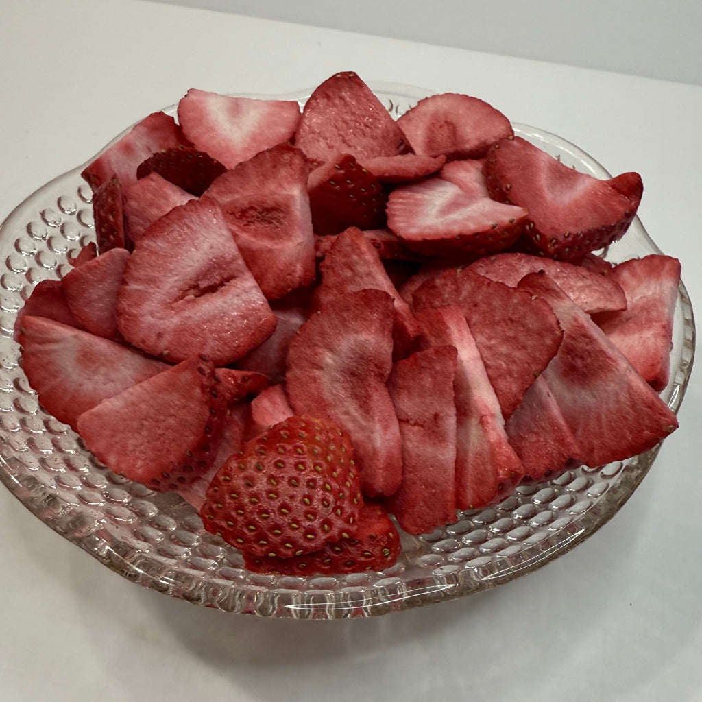 Freeze dried sliced strawberries on a decorative glass plate with a white background